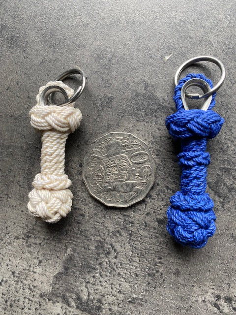 Current Little Bloody Ripper Knot key fobs in white and blue with stainless steel hardware beside a 50-cent coin
